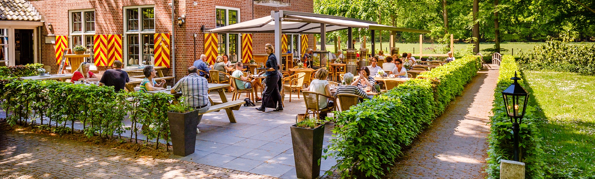 Gasten op het zonnige terras van de herberg