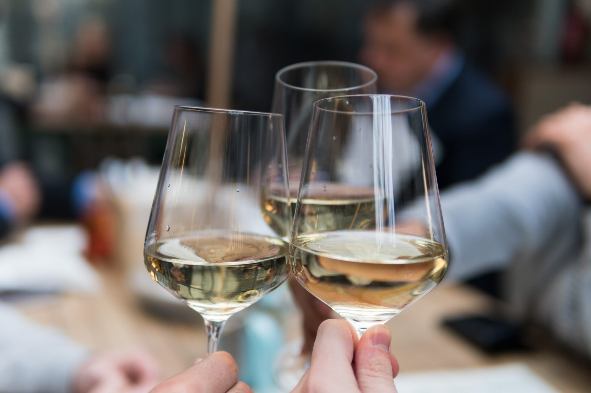 Gasten proosten met een glas witte wijn